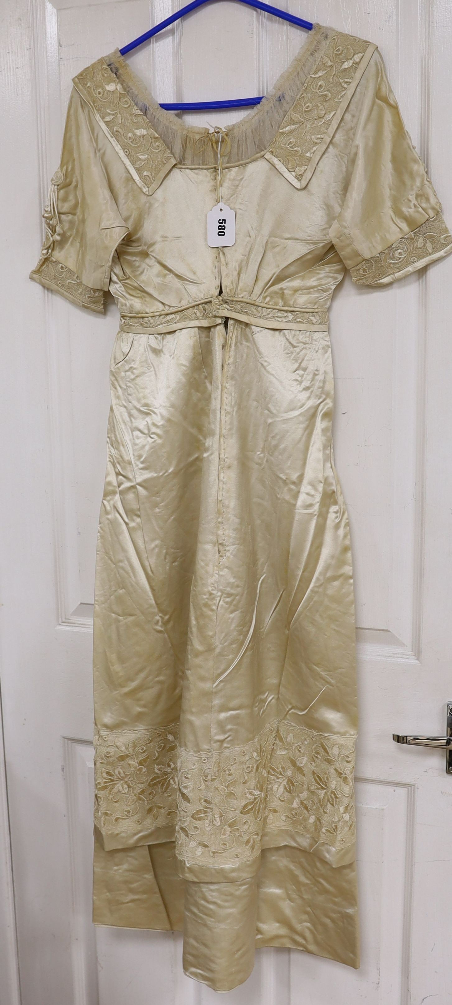 An Edwardian cream satin lady's dress with embroidered panels to base,sleeves front and collar